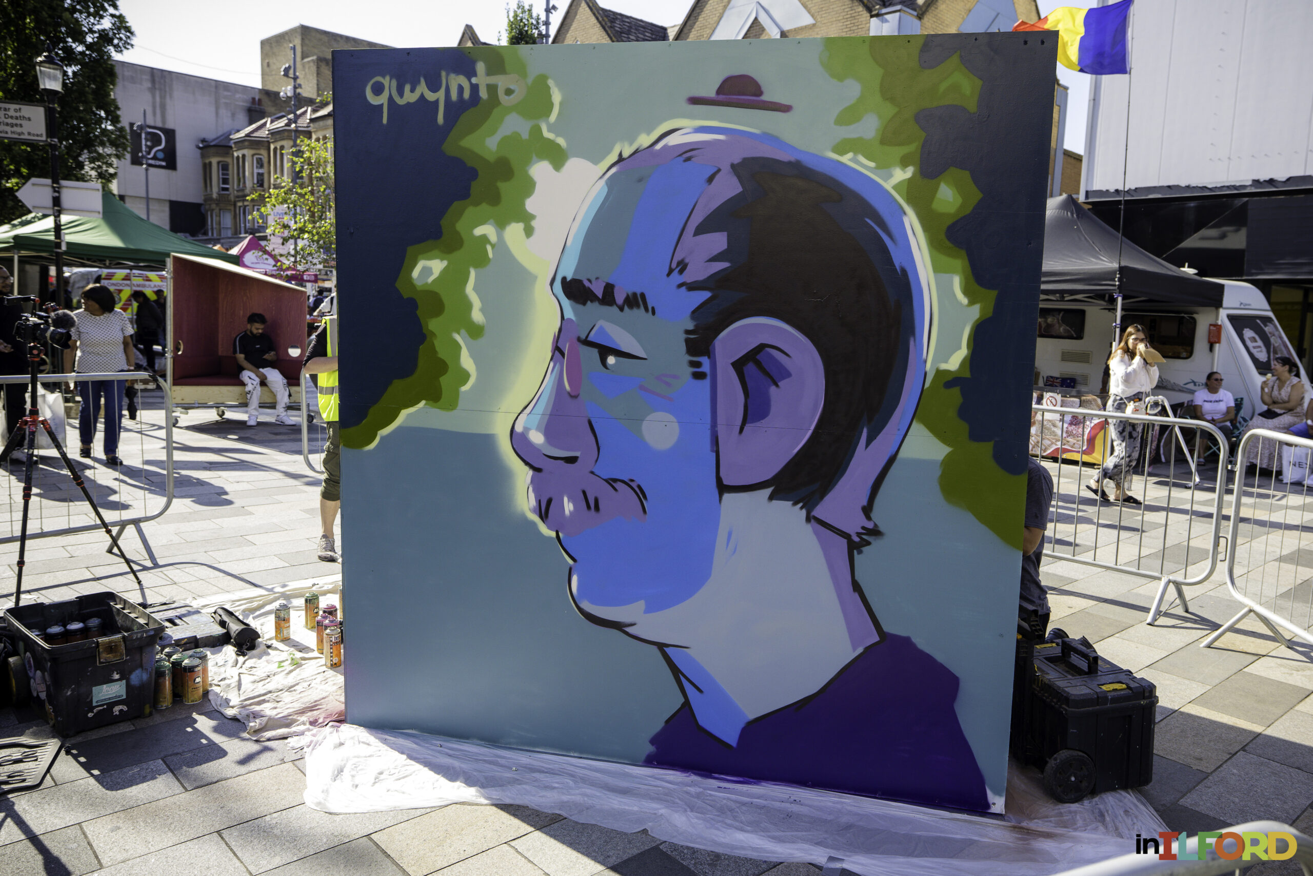 Artist painting a large mural during Ilford inColour in Ilford town centre