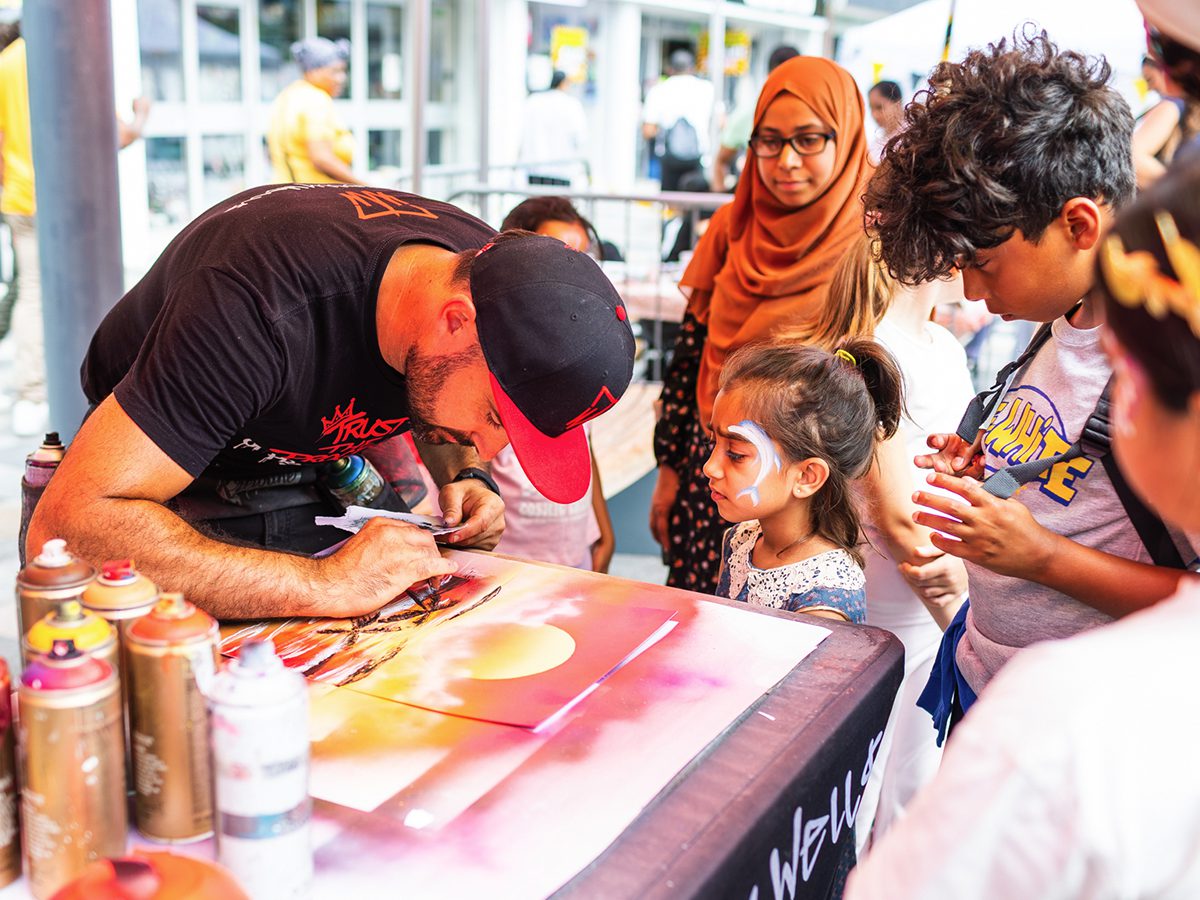 Tom Welly Wells demonstrating spray painting with children and families