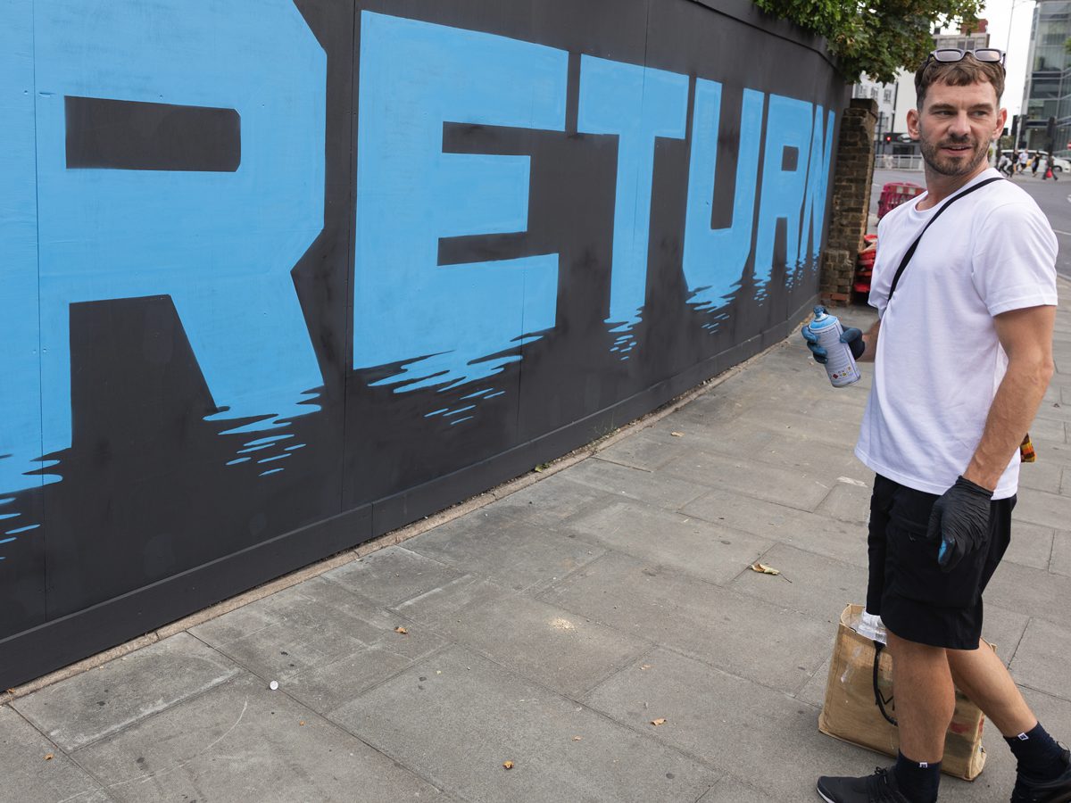 NEBOE painting the Ilford Hill mural as visitors pass by