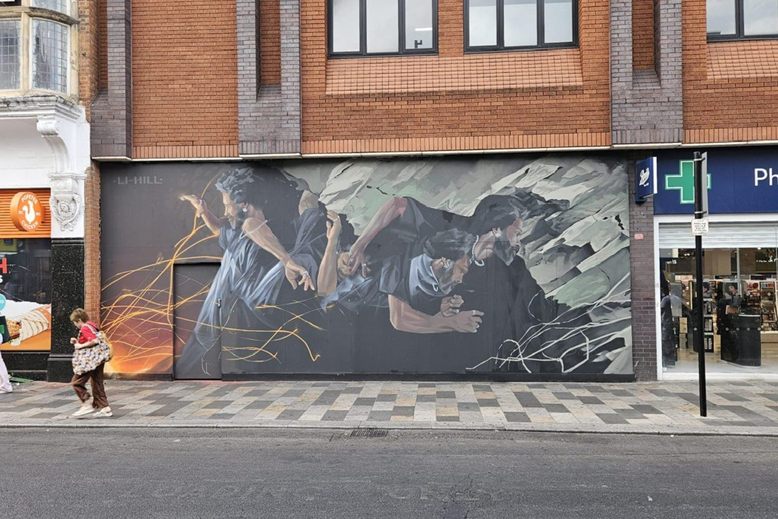 A second view of Aaron Li-Hill's High Road artwork with people walking past